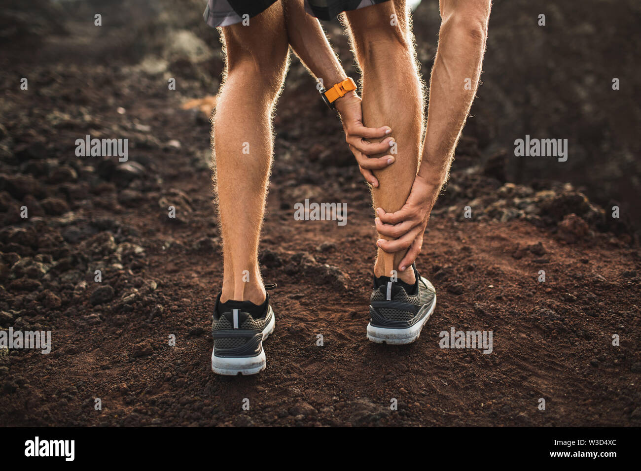 Male runner holding injured calf muscle and suffering with pain. Sprain