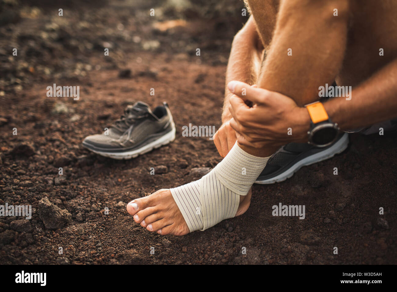 Man bandaging injured ankle. Injury leg while running outdoors. First