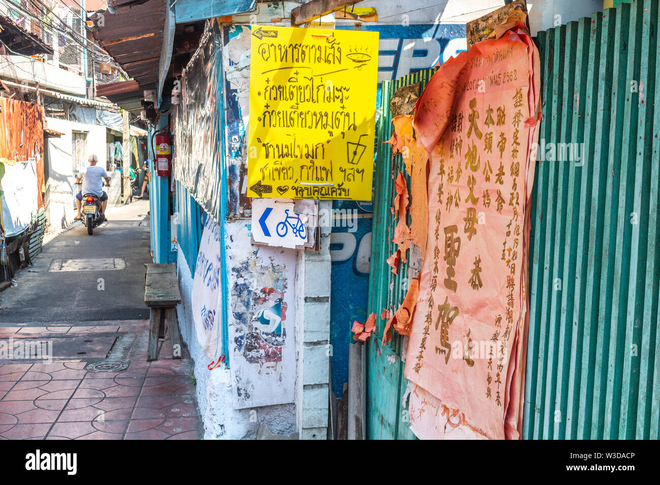 Bangkok, Thailand - April 14, 2019: Chinese and thai banners on the walls of a paved street in a residential neigborhood in central Bangkok Stock Photo