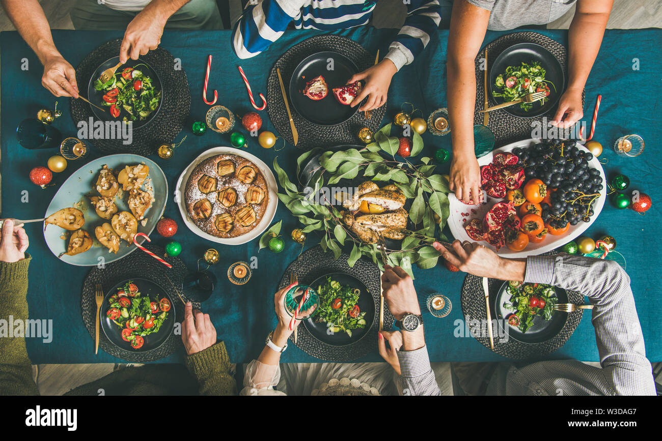 Human hands holding glasses with drinks and eating at Christmas Stock Photo