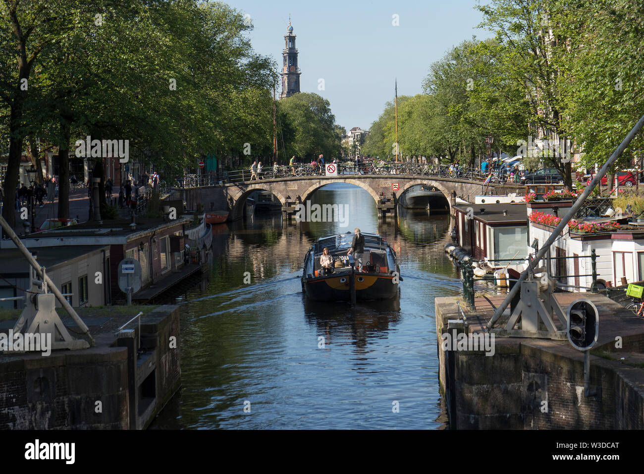 Amsterdam, Holland - June 22, 2019:  Boat sails by lock on the Prinsengracht with a view at the Westerkerk Stock Photo