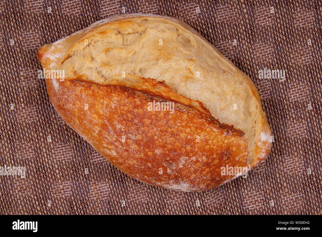 Top view of whole loaf sourdough bread lying on table covered with sacking Stock Photo