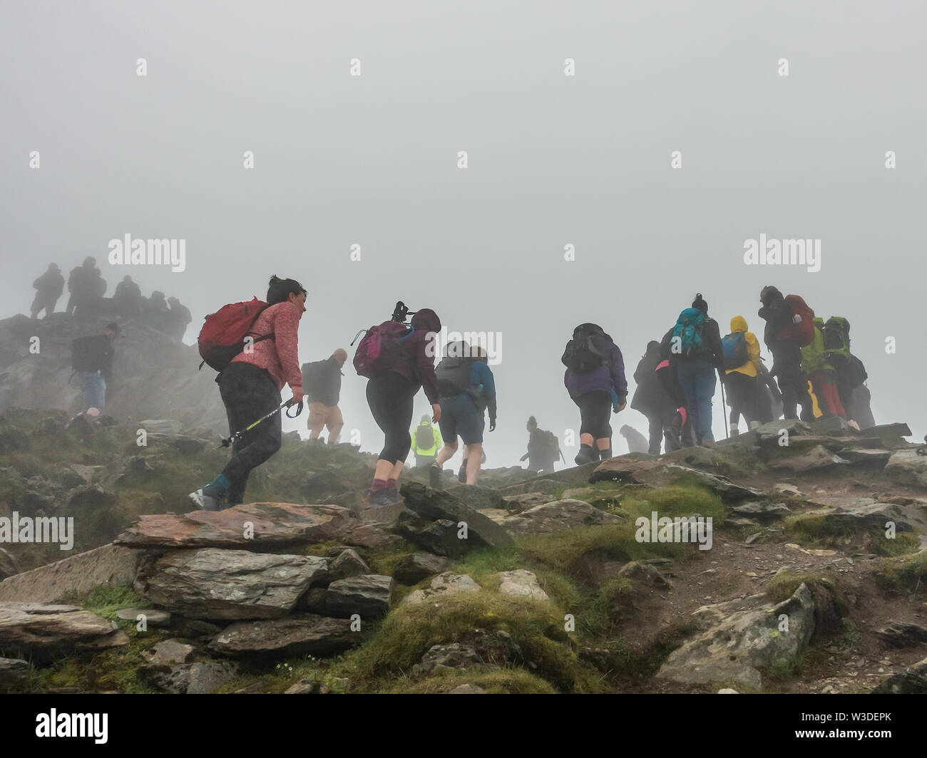 Mountain climbers reaching the summit of Mount Snowdon, in the