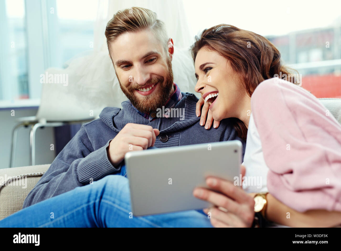 Happy couple using tablet and laughing Stock Photo