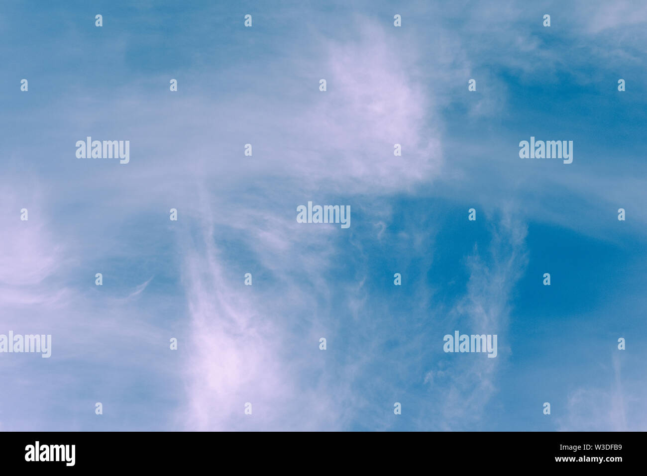 Beautiful light clouds over a clear blue sky background, wispy white clouds on a summer day