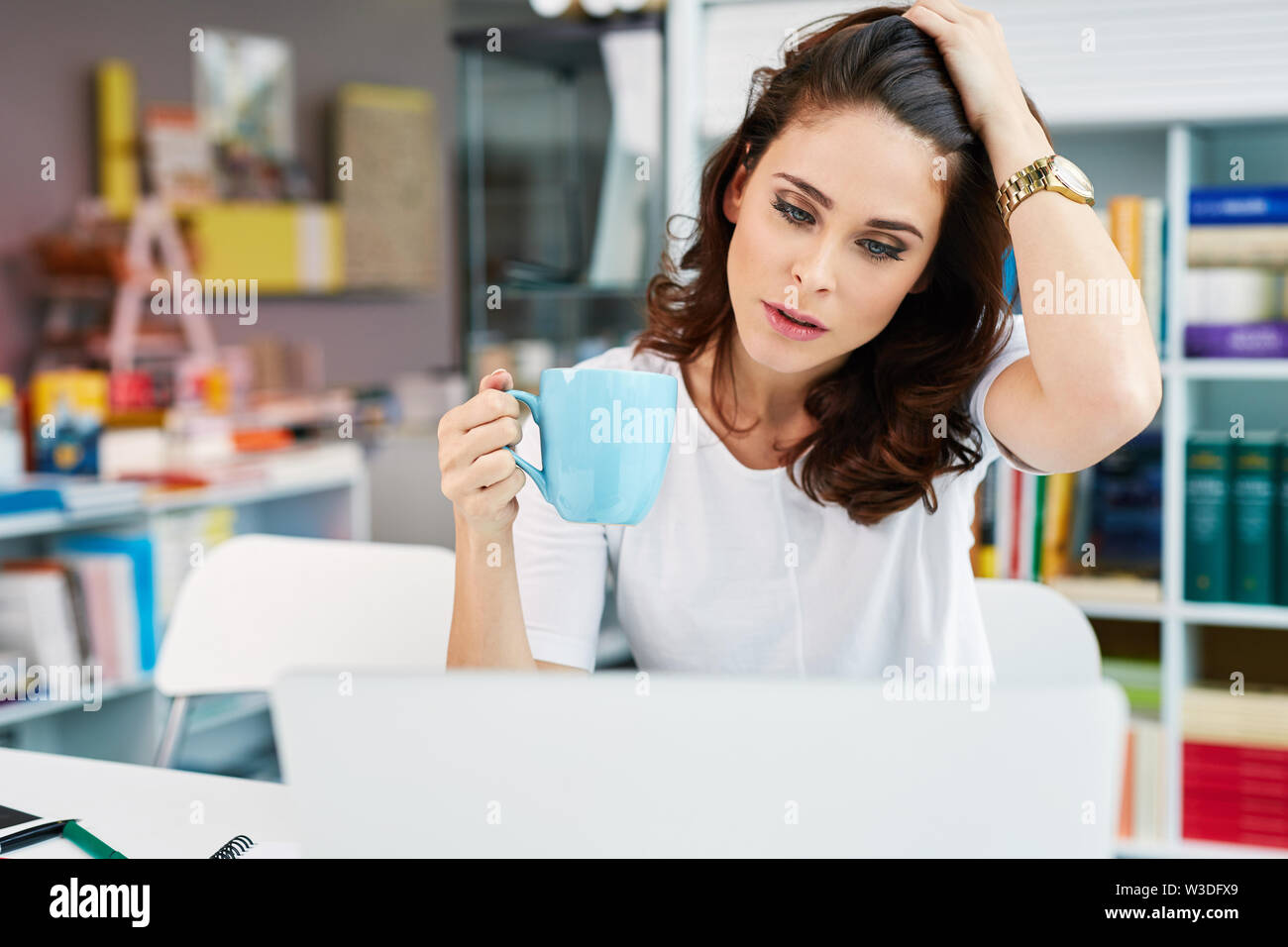 Worried woman working on her laptop at office Stock Photo