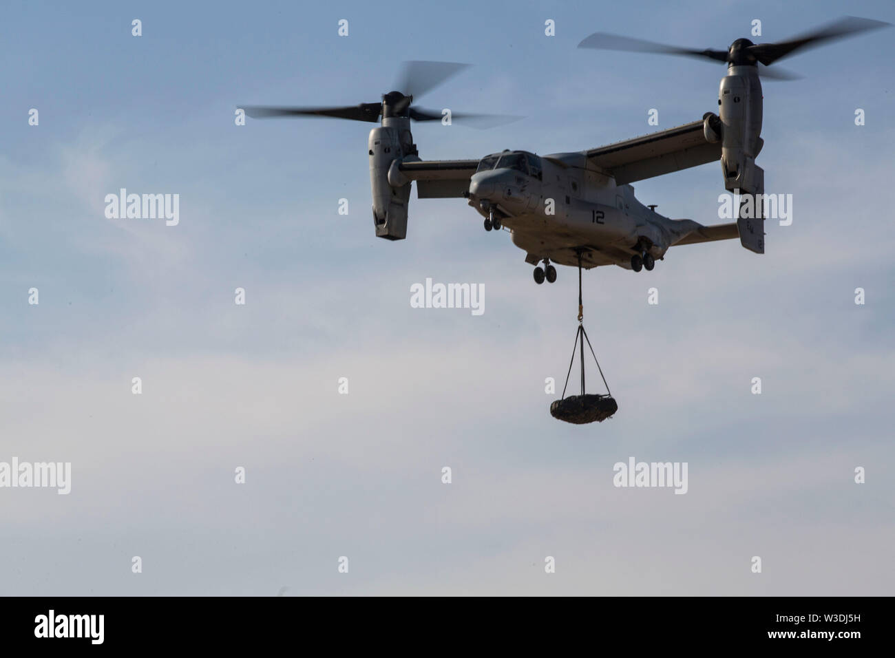 A U.S. Marine Corps MV-22B Osprey with Special Purpose Marine Air-Ground Task Force-Crisis Response-Africa 19.2, Marine Forces Europe and Africa, conducts an external lift during helicopter support team training on Moron Air Base, Spain, July 9, 2019. The exercise was conducted to increase interoperability between the aviation combat element and logistics combat element. SPMAGTF-CR-AF is deployed to conduct crisis-response and theater-security operations in Africa and promote regional stability by conducting military-to-military training exercises throughout Europe and Africa. (U.S. Marine Cor Stock Photo