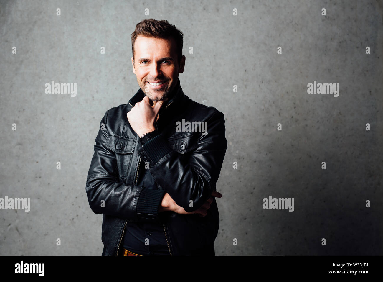 Young handsome man smiling  isolated against concrete wall Stock Photo