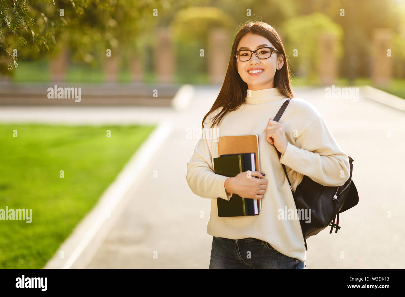 Happy girl posing with backpack carrying books Stock Photo - Alamy