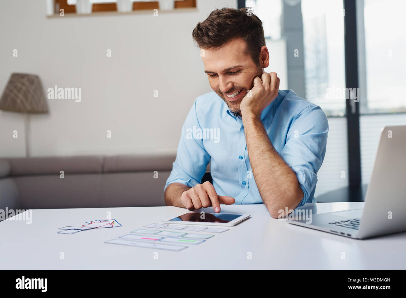 Handsome web designer testing usability on tablet and laptop in home office Stock Photo