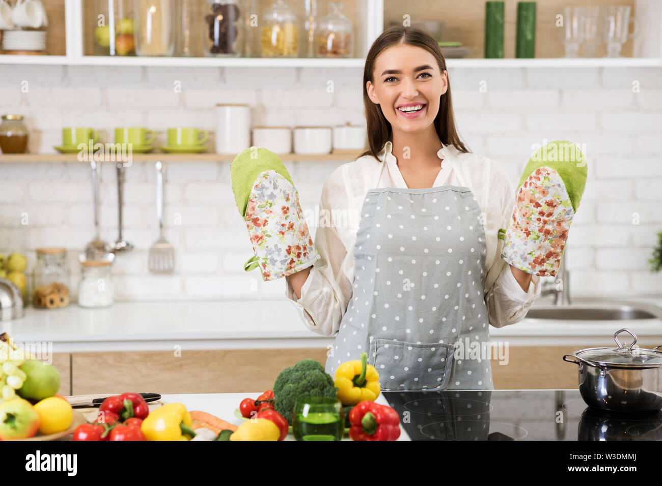 Happy housewife with oven mittens and apron Stock Photo