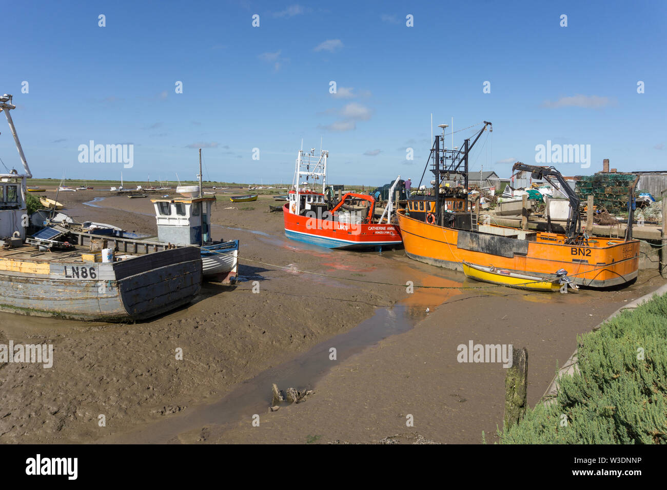 Fishing boats at low tide in the tidal harbour of Brancaster Staithe, Norfolk, UK Stock Photo