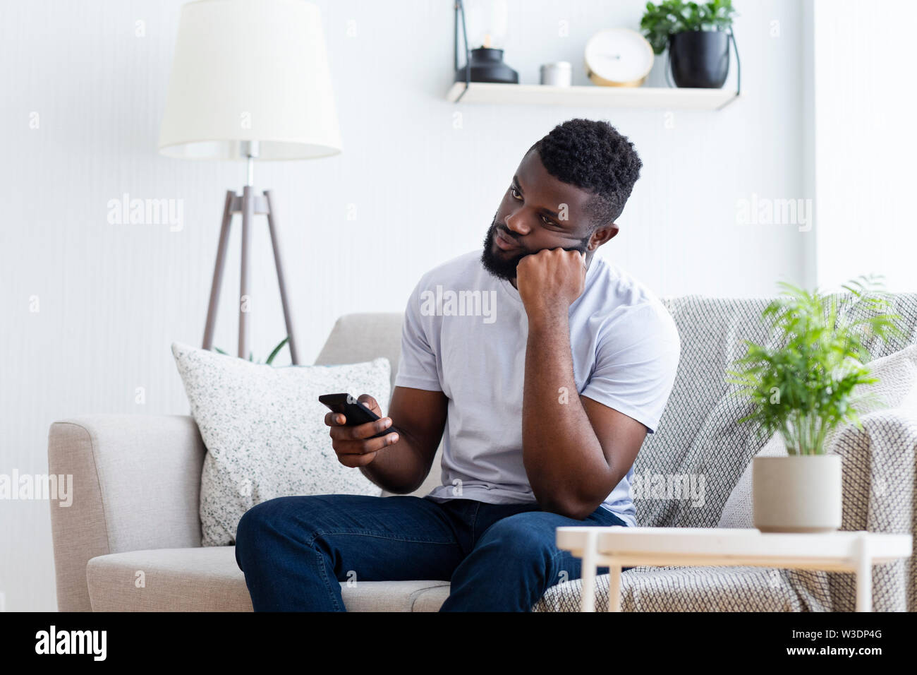 Young man watching tv, using remote control to switch channels Stock Photo