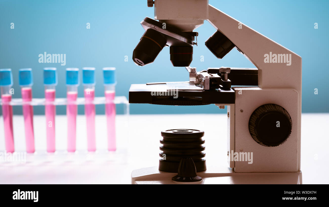 Microscope and test tubes on laboratoy table Stock Photo - Alamy