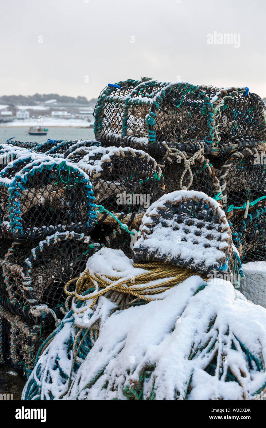 Crab-pots stacked on Old Quay, Hugh Town, St. Mary's, Isles of Scilly, UK, under a rare fall of snow Stock Photo
