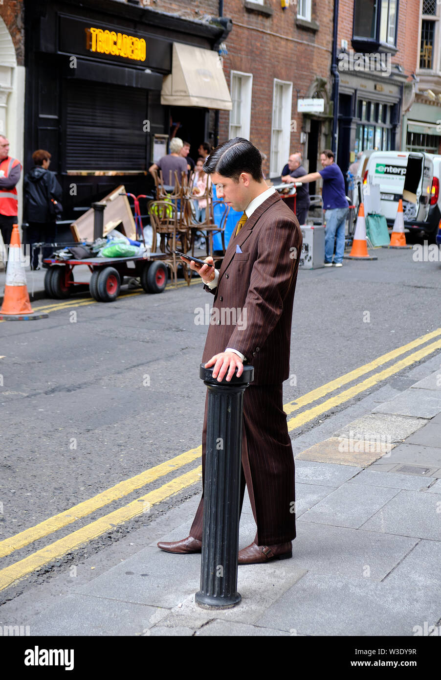 Dublin, Ireland, July 6, 2017: Actor in a time piece during a filming break looking at cell phone in front of Trocadero. Crew visible in background Stock Photo