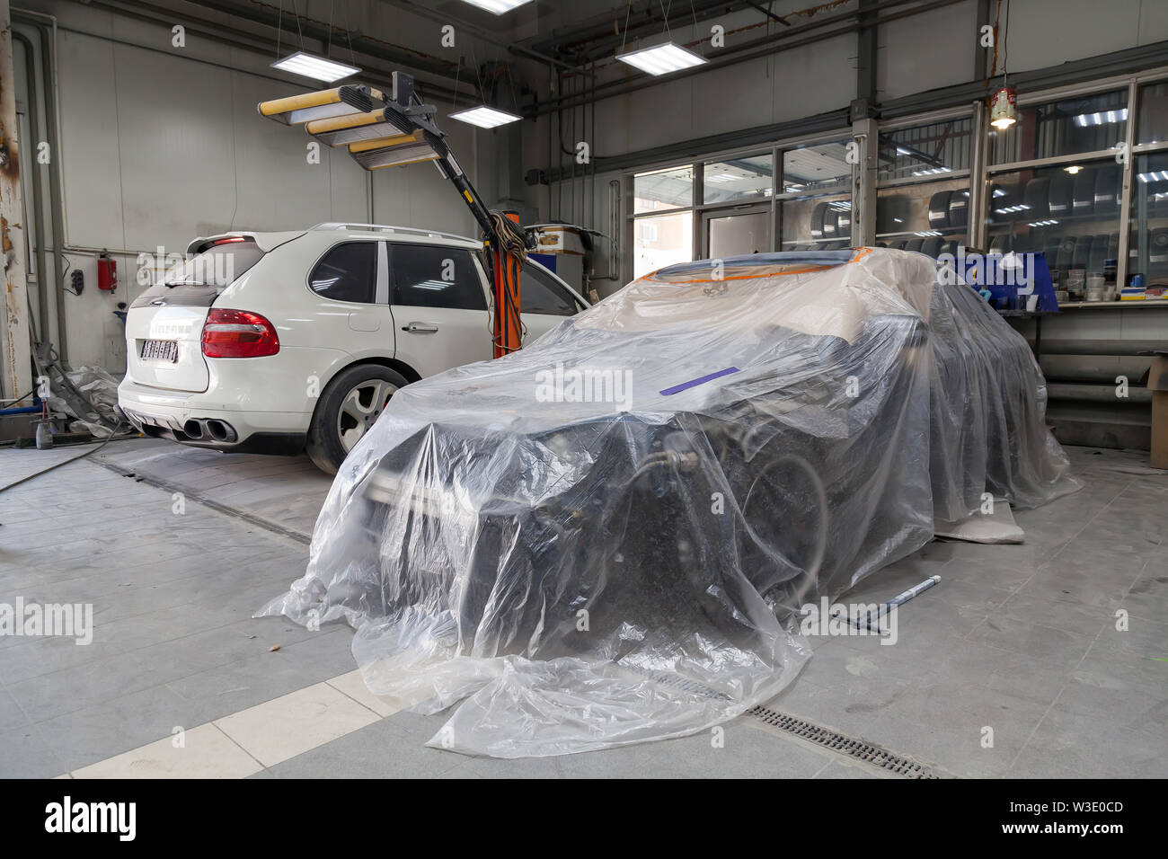 A bluse sedan car is completely covered in film and adhesive tape to  protect against splash during painting after an accident in a workshop for  body r Stock Photo - Alamy