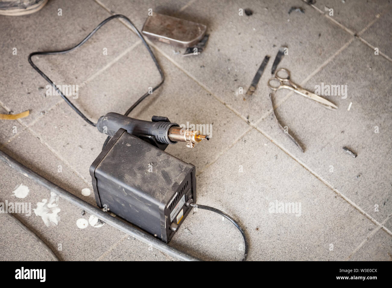 Industrial soldering gun of black color on the floor among dust and