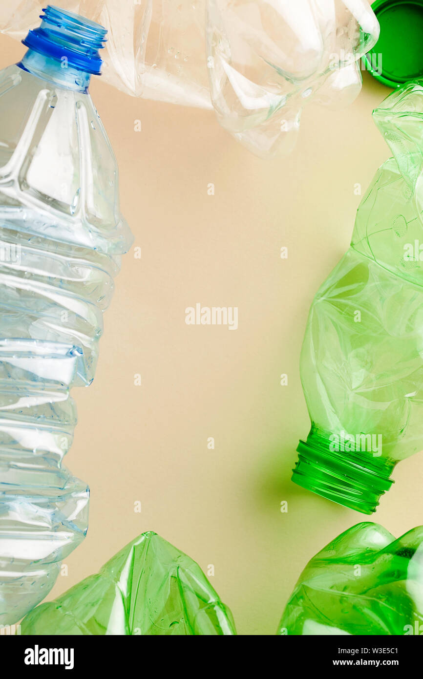 Used empty plastic water bottles crumpled for sorting (segregating) and recycling on coral pink background top view with copy space Stock Photo