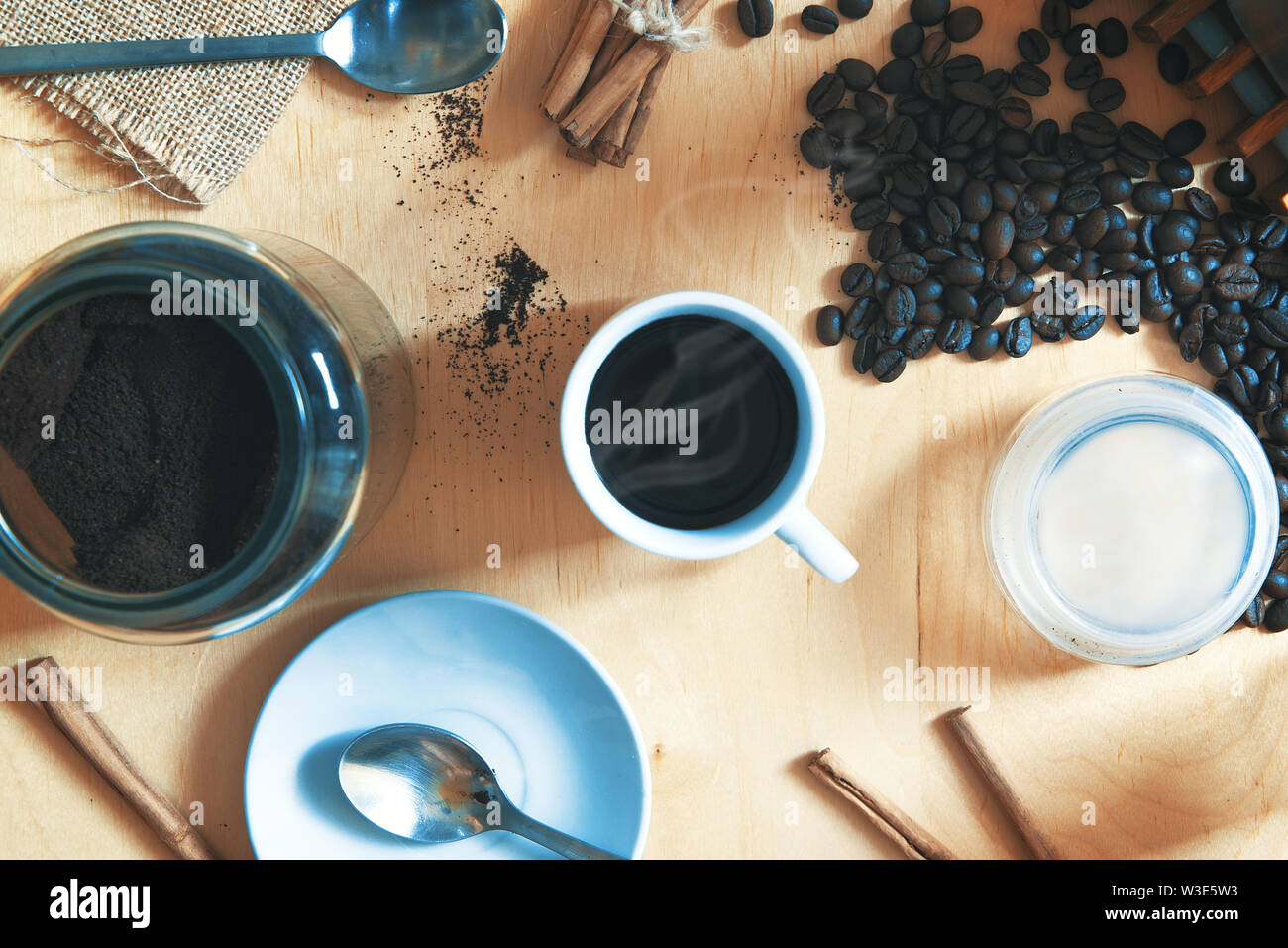 Cup with expresso cafe on a rustic wooden table. Next, some ground coffee and beans with cinnamon. Overhead shot for a top view. Stock Photo