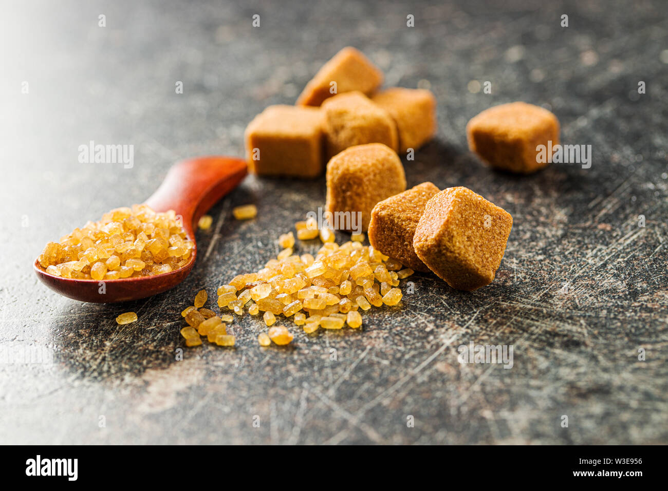 Crystalized brown sugar and sugar cubes on old kitchen table. Stock Photo