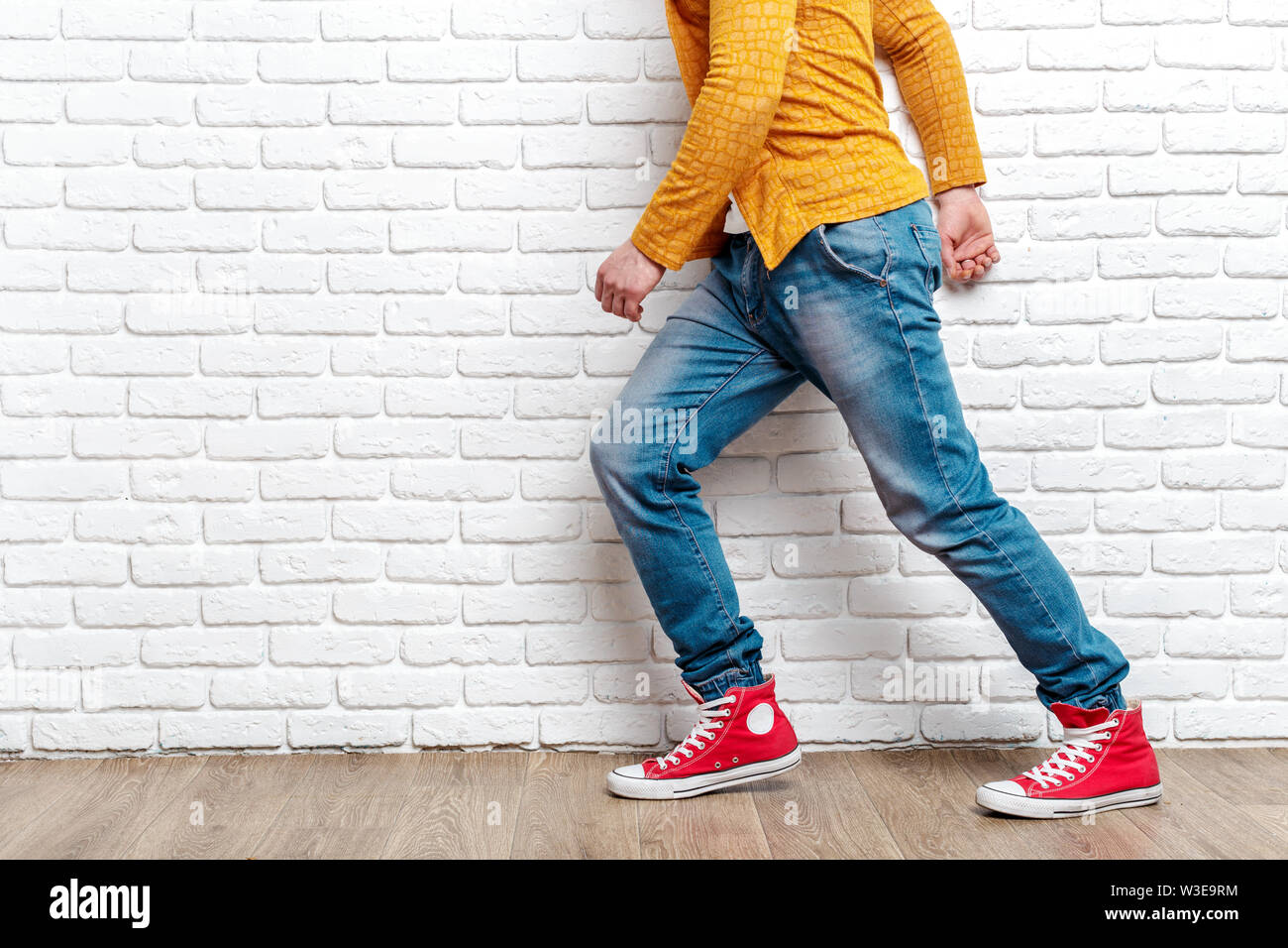 Young fashion man's legs in jeans and sneakers on wooden floor Stock Photo  - Alamy