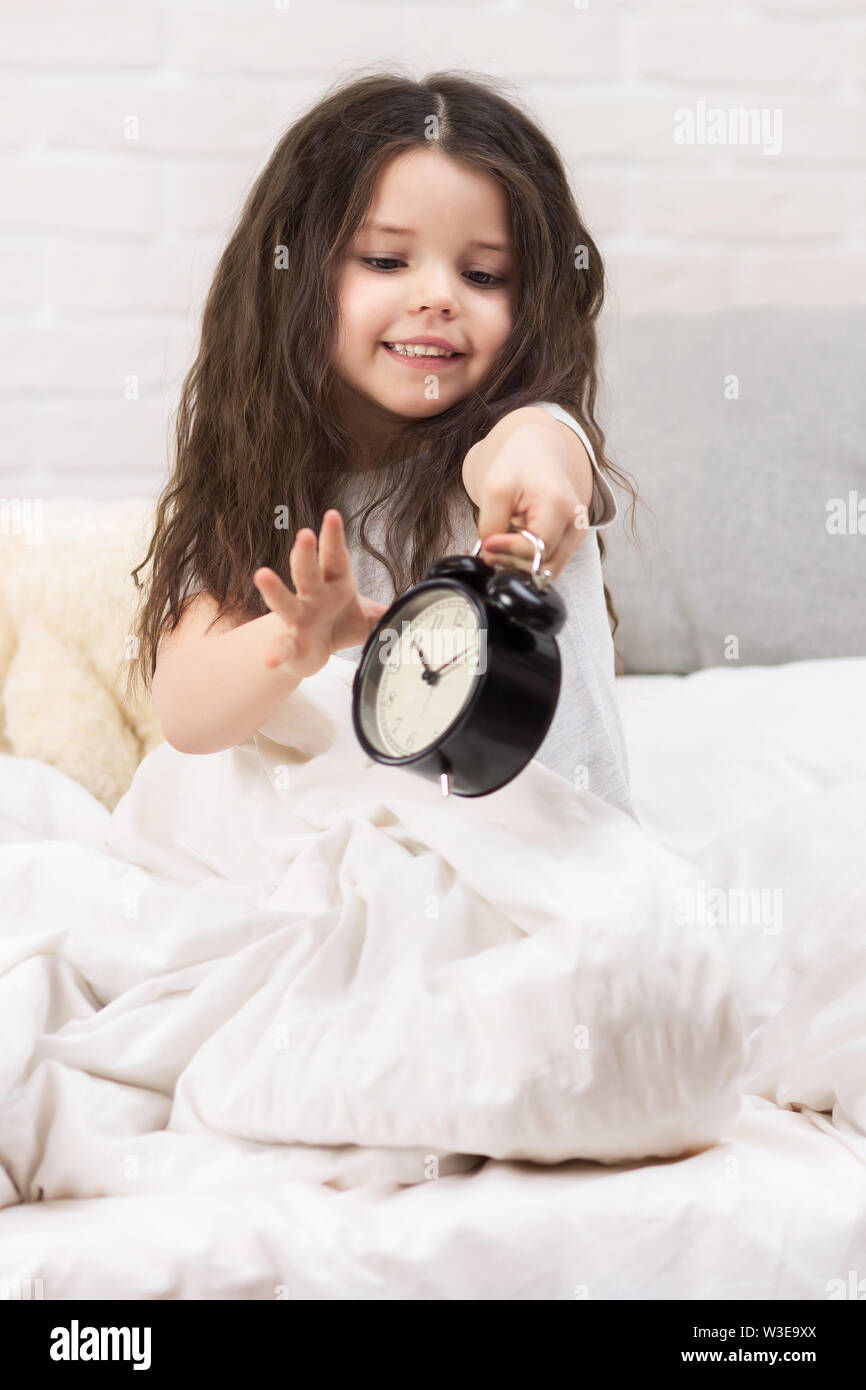 Cute Smiling Little Child Girl In Pyjamas With Clock In Bed Good