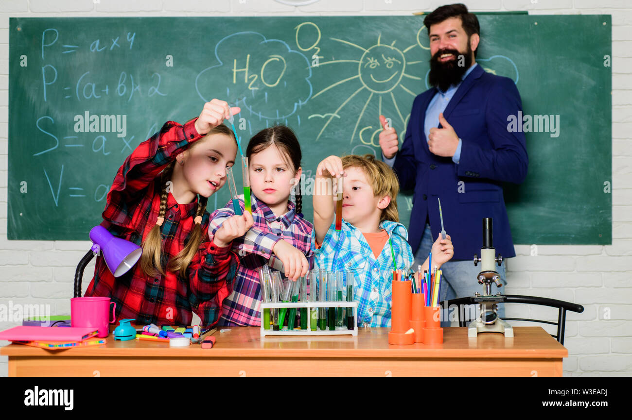 Little kids learning chemistry in school laboratory. school kids scientist studying science. happy children teacher. back to school. students doing science experiments with microscope in lab. team. Stock Photo