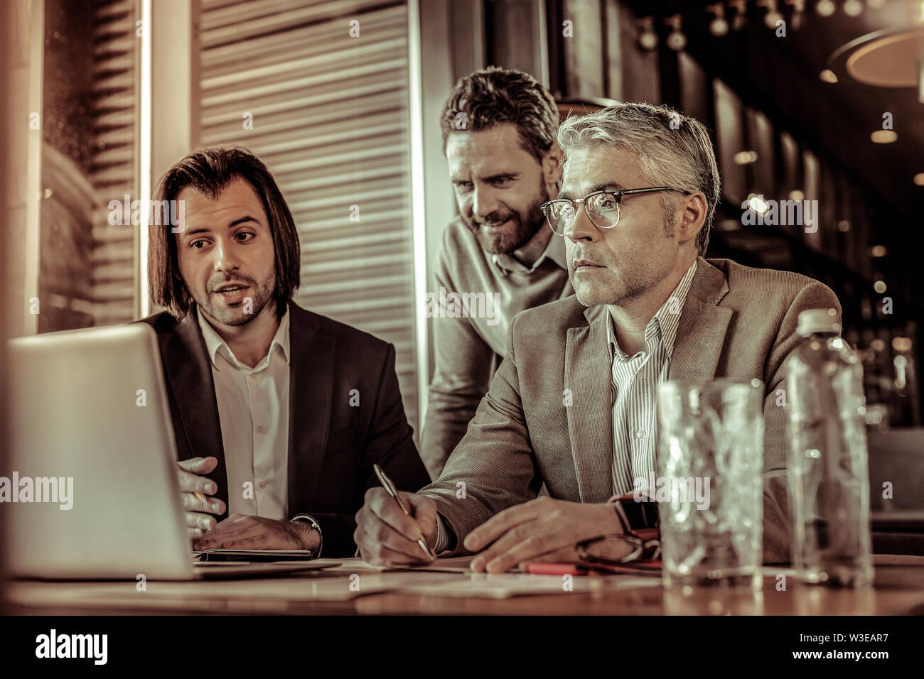 Attentive aged businessman making notes during conference Stock Photo