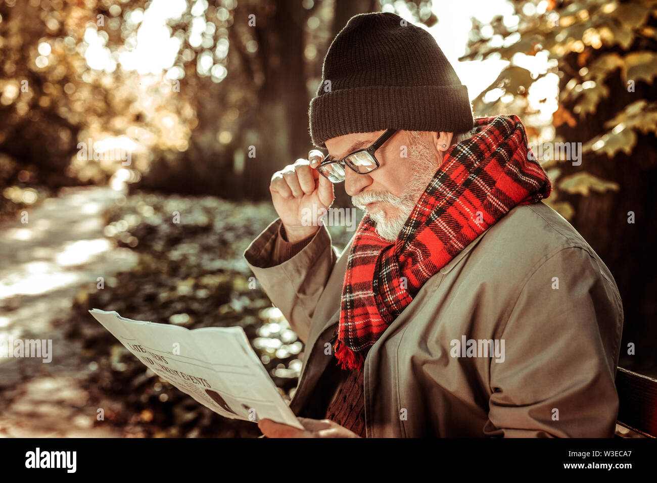 Bearded elderly man sitting on the bench with a newspaper Stock Photo ...