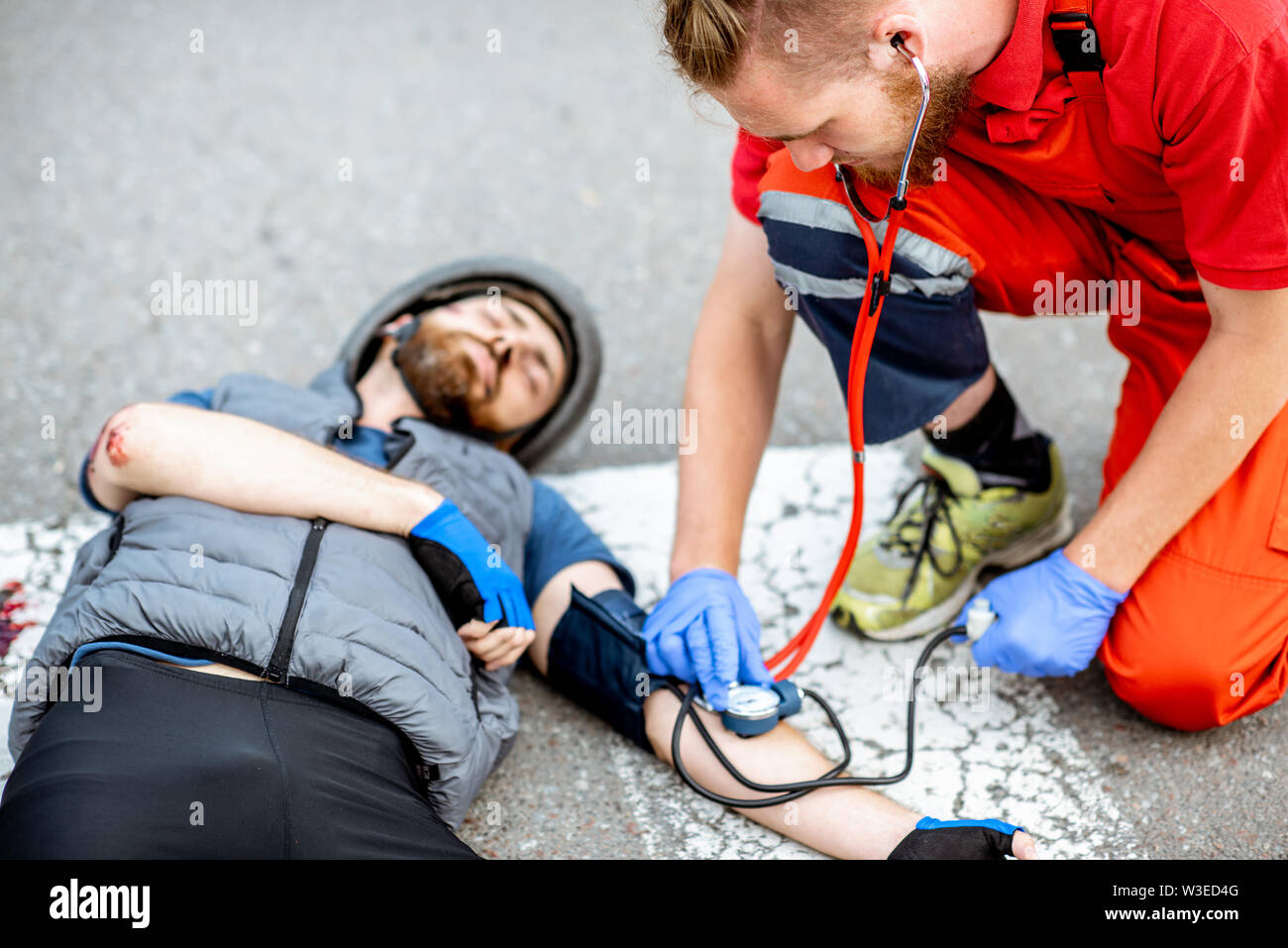 Medic applying first aid to the injured cyclist lying on the pedestrian ...