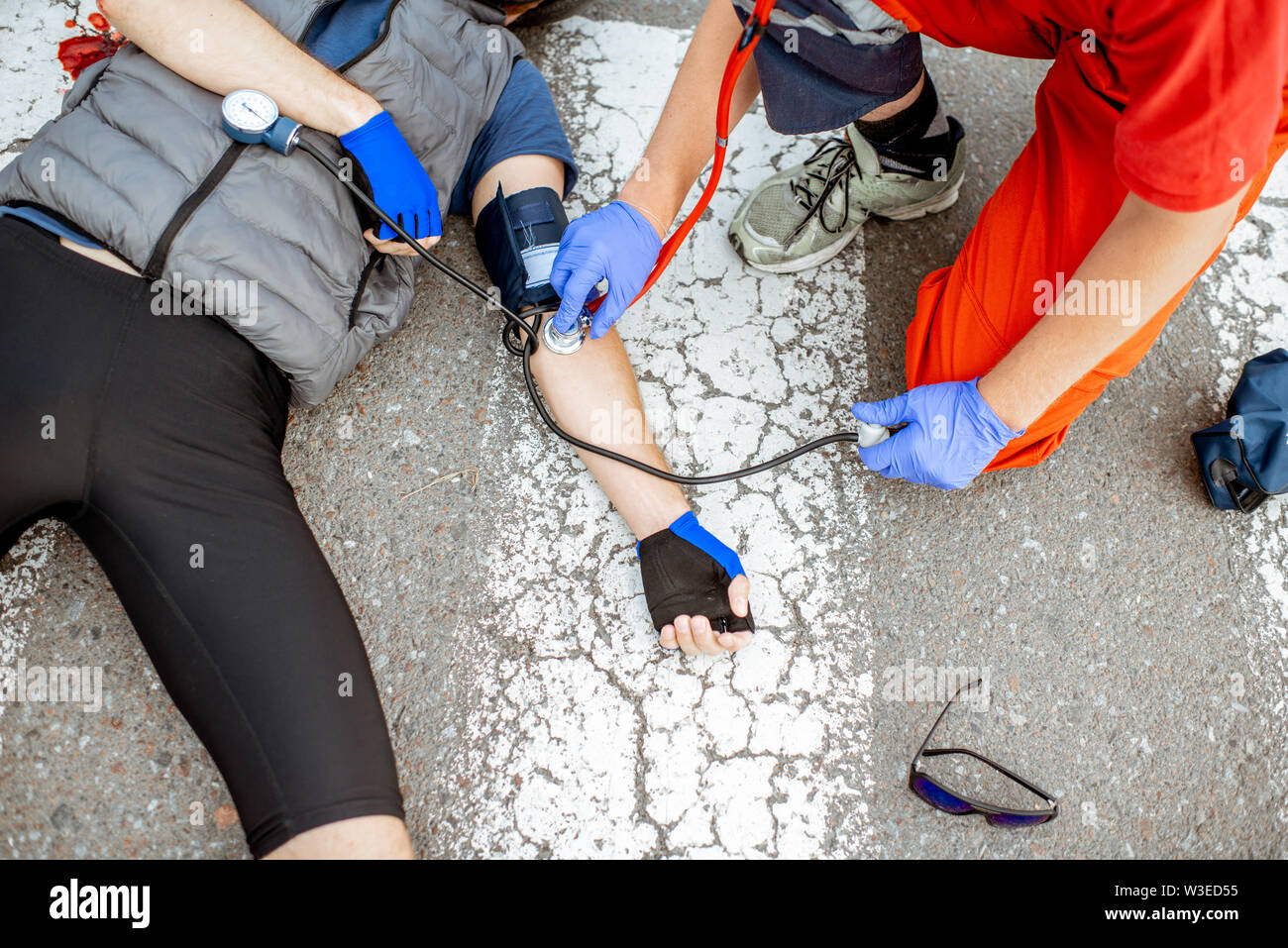 Medic applying first aid to the injured cyclist lying on the pedestrian ...