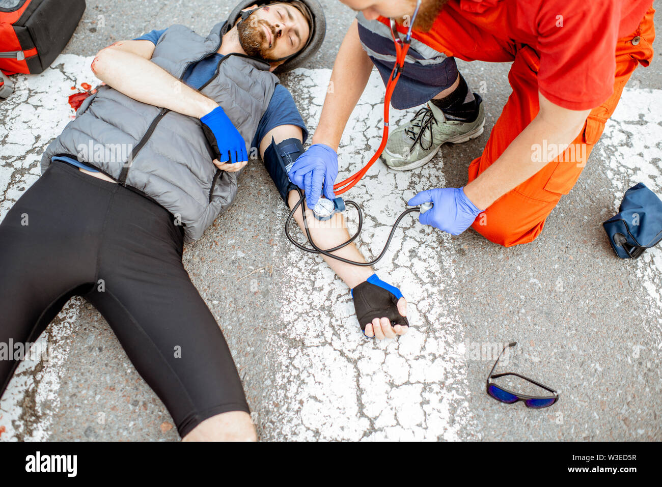 Medic applying first aid to the injured cyclist lying on the pedestrian ...