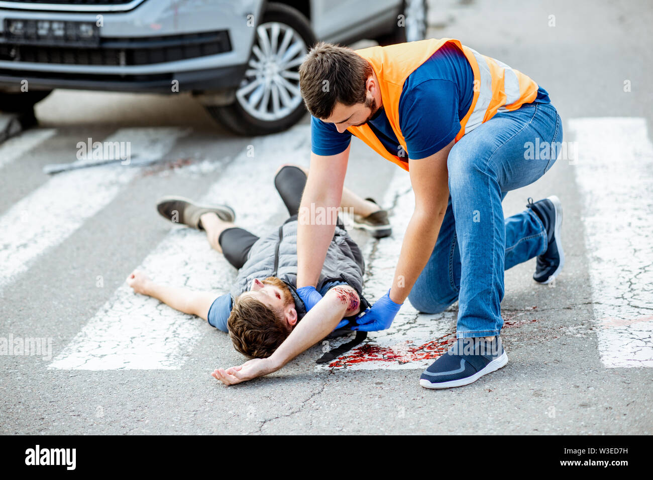 Man applying first aid to the injured bleeding person, wearing