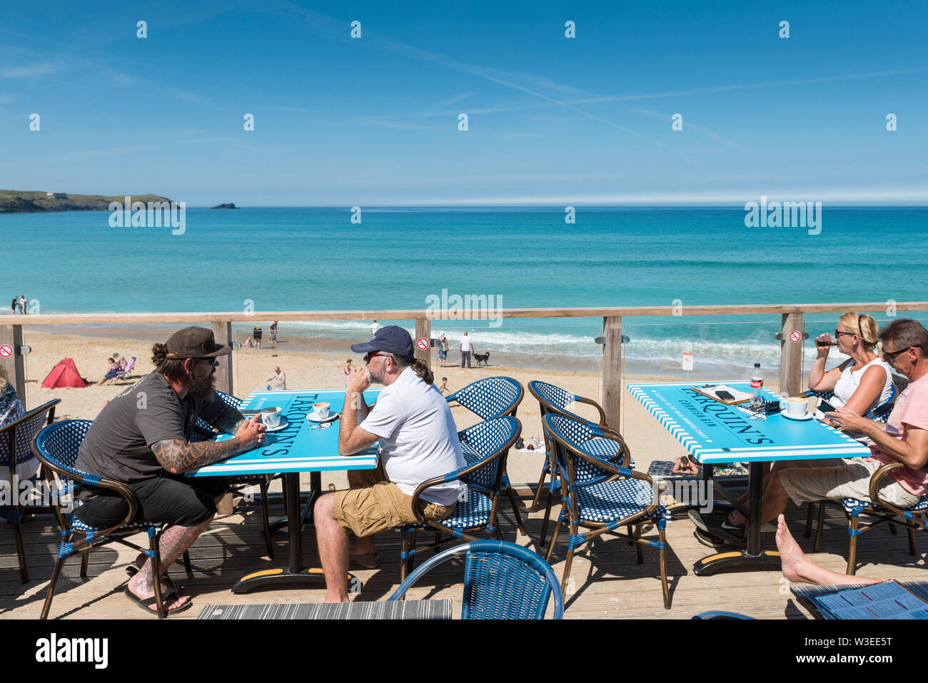 Holidaymakers sitting on the terrace of the Fistral Beach Bar and relaxing in the mid morning sunshine in Newquay in Cornwall. Stock Photo