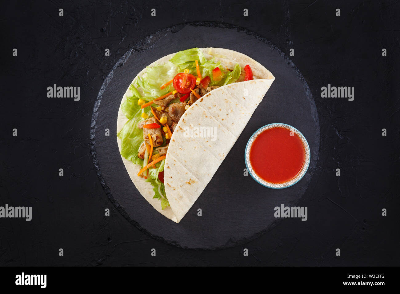 Burritos wraps with chicken and vegetables on black slate. Chicken