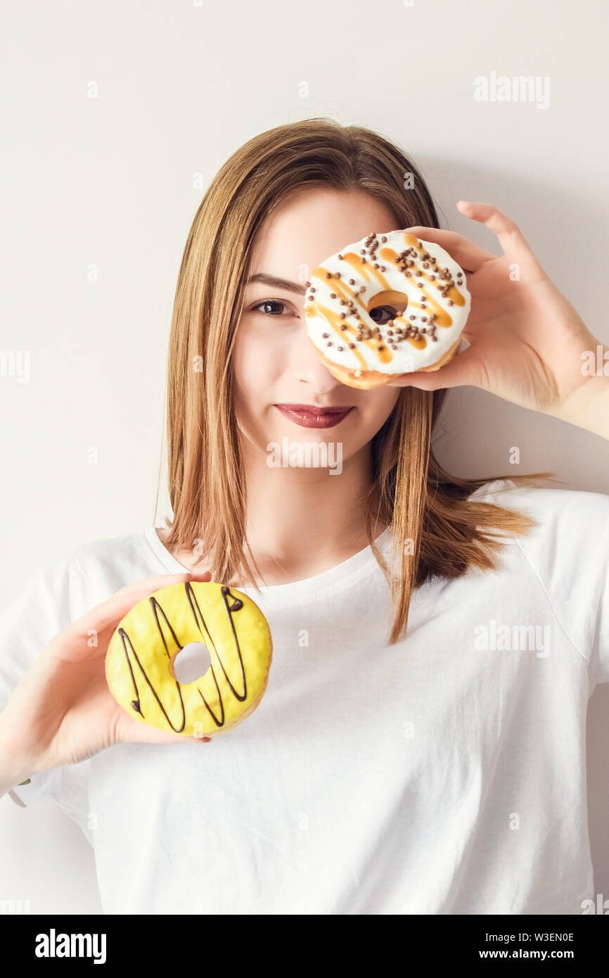 Beautiful girl holding donuts and having fun on white background. Funny joyful woman with sweets, dessert. Diet, dieting concept. Junk food, Slimming, Stock Photo