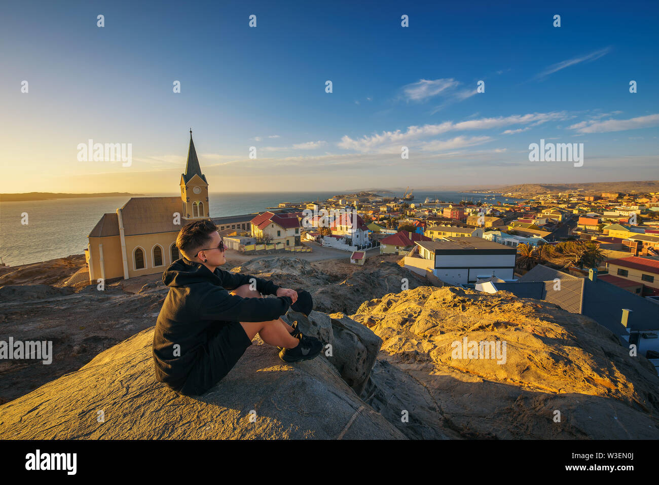 Tourist on top of a hill enjoys the view of Luderitz in Namibia at sunset Stock Photo