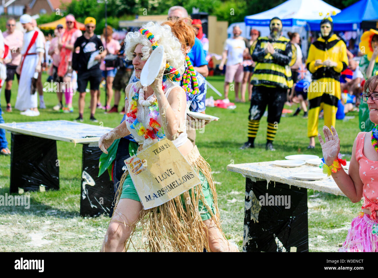 Custard covered young woman team member throwing custard pie at unseen