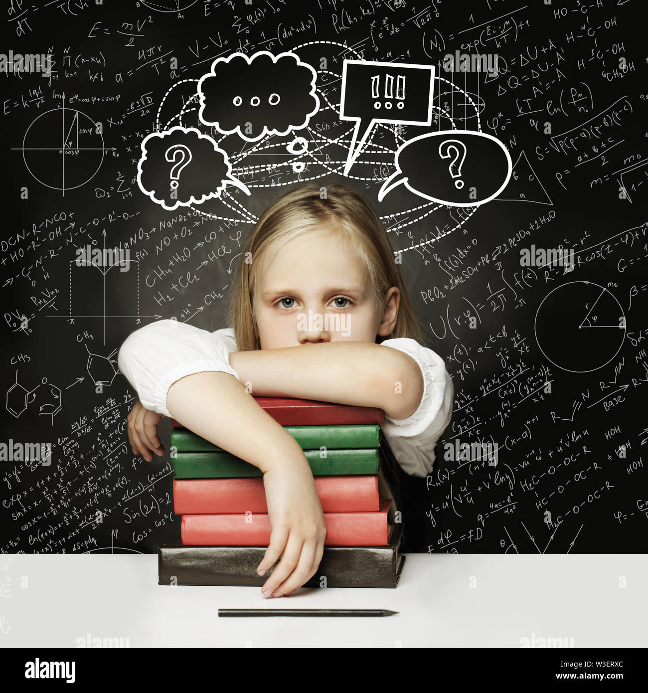 Tired child with books. little student thinking with thumb up and empty speech clouds bubbles on chalkboard Stock Photo
