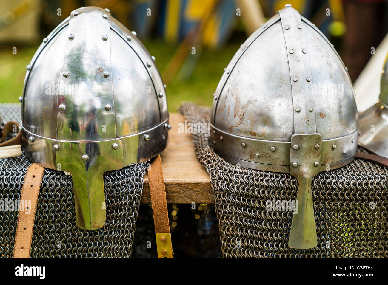 Two variations of Norman Spangenhelm helmets and some chain mail, on display at living history event. Helmets resting on chain mail draped over table. Stock Photo