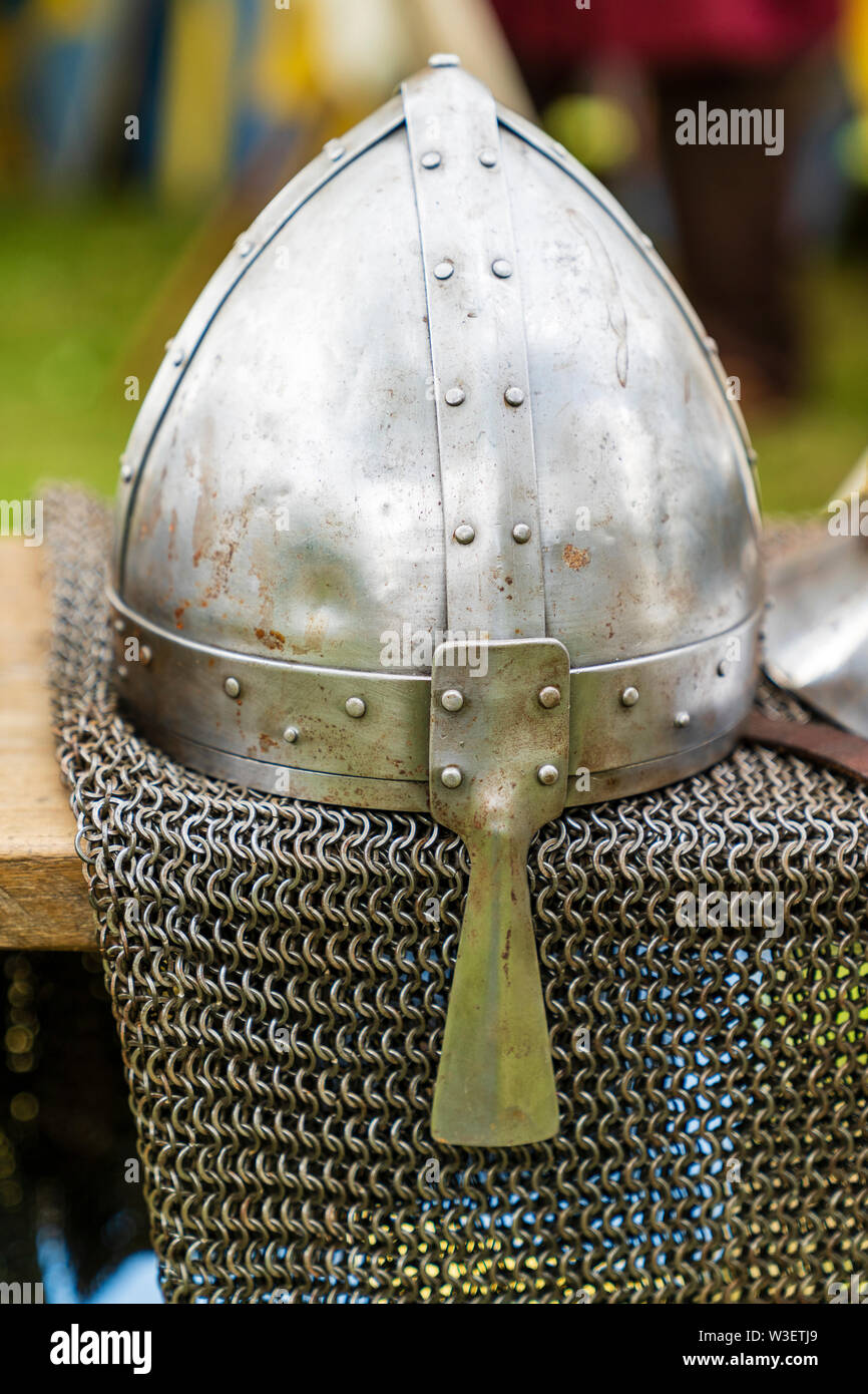 11th century Norman Spangenhelm helmets and some chain mail, on display at living history event. Helmet resting on chain mail draped over table. Stock Photo