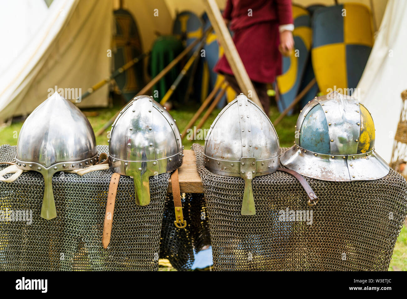Three variations of Norman Spangenhelm helmets with a Circular Reinforced Capelina Helmet and some chain mail, on display at a living history event. Stock Photo
