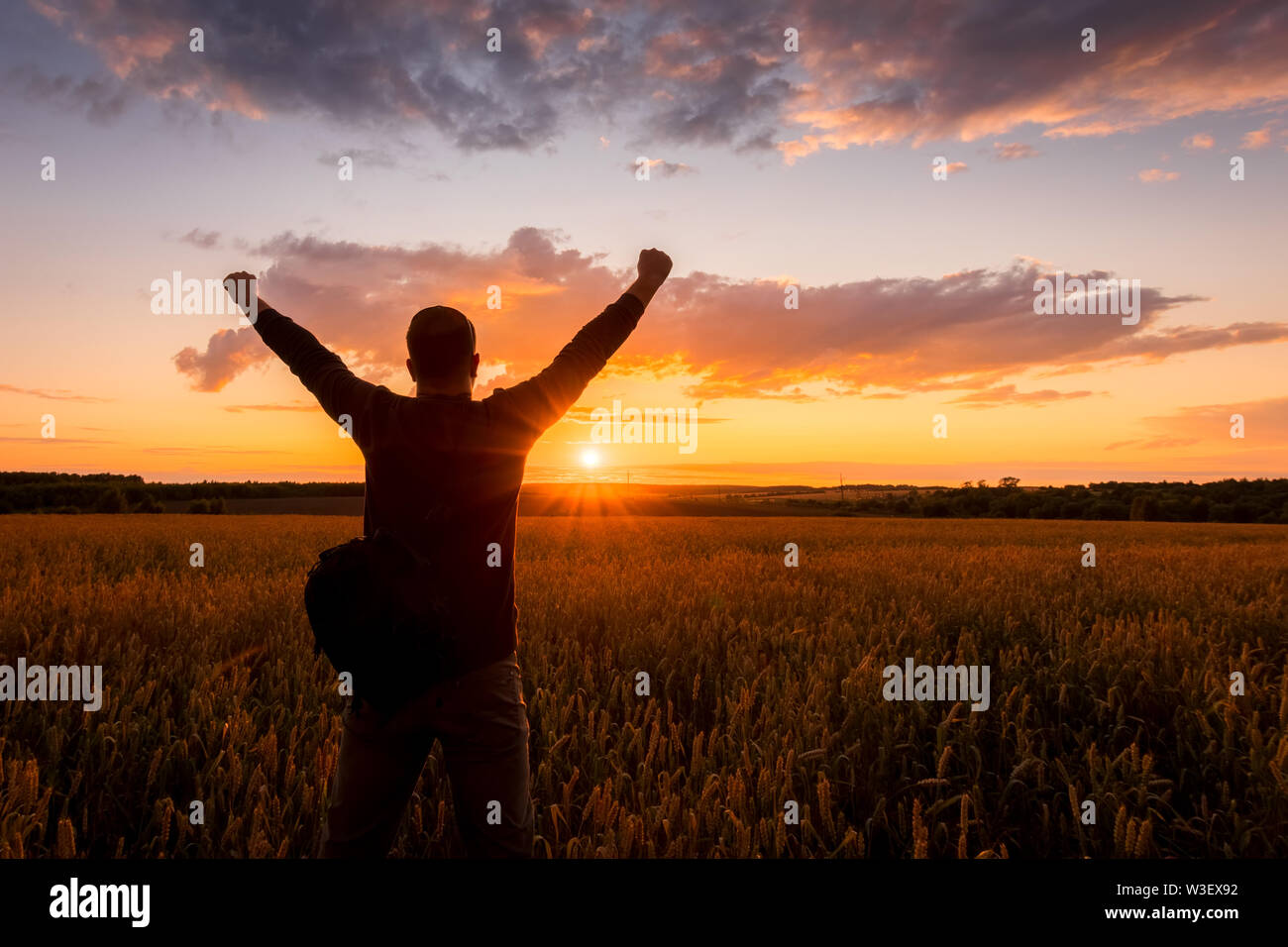 Silhouette of a man raise his hands up to sunset on the field with ...