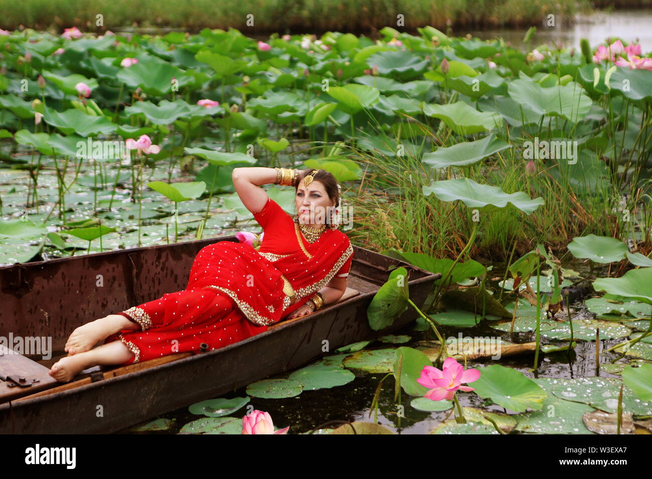 Beautiful woman in red sari on lotus lake Stock Photo