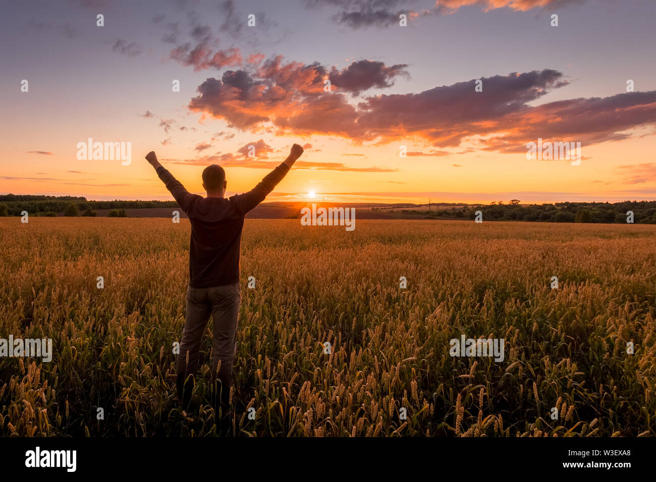 Silhouette of a man raise his hands up to sunset on the field with ...