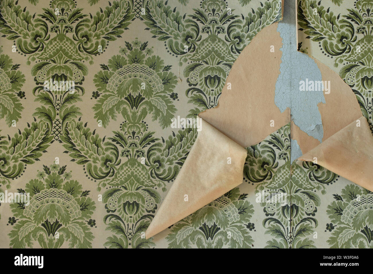 Wall with torn wallpaper in old house. Vintage background pattern. Stock Photo