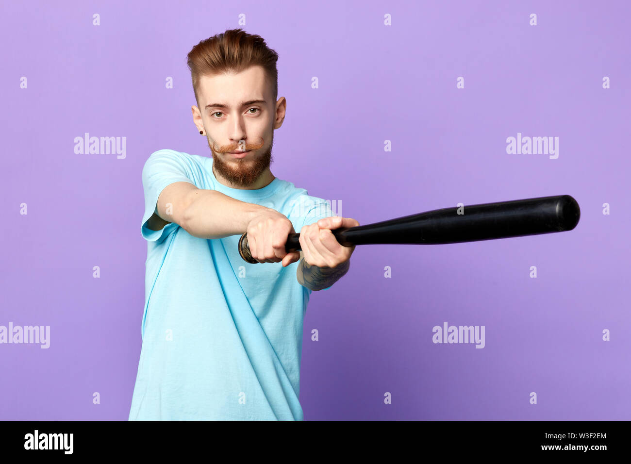 young sporty man holding baseball bat and looking at camera isolated on blue background. close up portrait. free time, spare time. lifestyle, copy spa Stock Photo