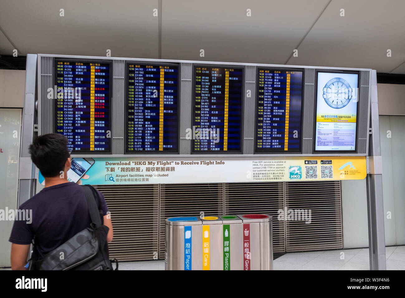Lantau, Hong Kong  - August 26, 2018 : Airline passengers look at airplanes departure information panel at Hong Kong International Airport Stock Photo