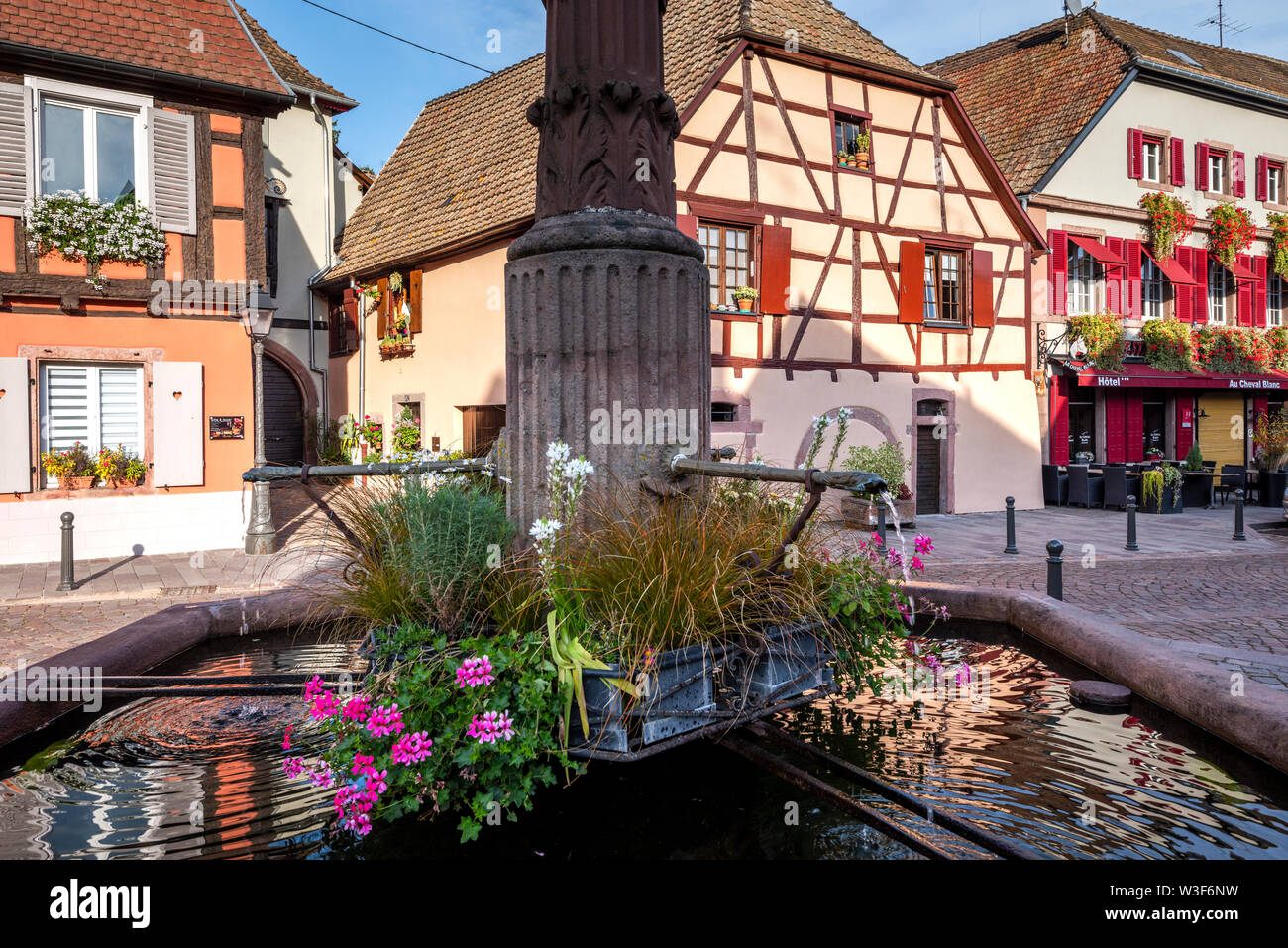scenic square in the wine village Ribeauvillé, Alsace, France, flower decorated well with timbered houses Stock Photo